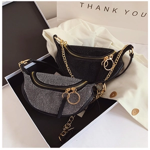 Detail of luxury rhinestone half-moon waist bag with gold chain strap on gift box