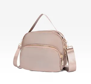 Side view of khaki waterproof nylon crossbody bag with multiple metal zippers