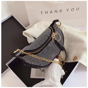 Detail of black crescent rhinestone bag with gold zipper inside a luxury gift box