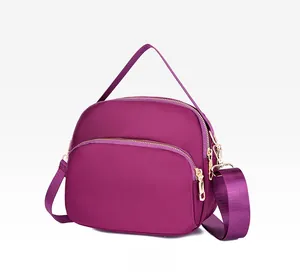 Detail view of purple waterproof nylon crossbody bag with dual zipper compartments