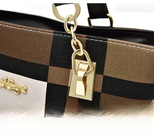 Detailed macro view of the gold-tone logo and plaid canvas texture on a shoulder bag