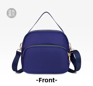 Front view of a navy blue waterproof oxford crossbody bag with golden metal hardware