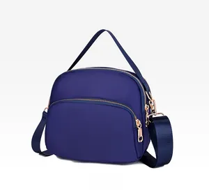 Detail view of the waterproof dark blue nylon crossbody bag featuring multi-layer zippers