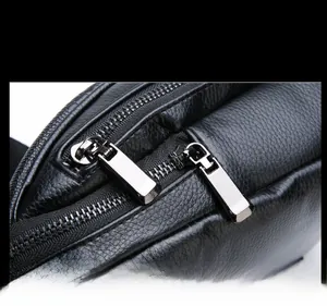 Close-up of durable silver metal dual zippers on black crocodile pattern leather chest bag