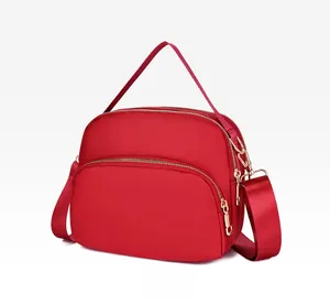Side view of red waterproof nylon crossbody bag showing three zipper compartments