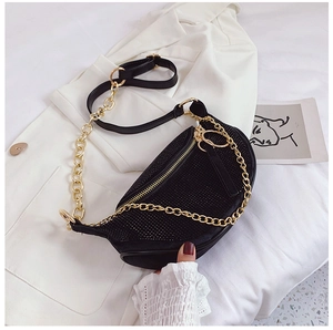 Close-up of black rhinestone crossbody bag with gold chain strap on white blazer