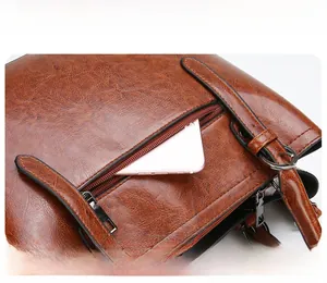 Detailed macro view of the brown patent leather tote with a functional zipper front pocket