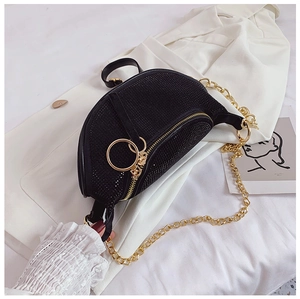 Macro shot of black rhinestone crescent bag with gold chain on a white blazer