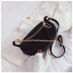 Detailed macro of black crescent rhinestone bag with gold chain and zip on white jacket