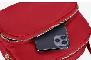 Detail of red nylon crossbody bag showing multiple pockets with a smartphone for size