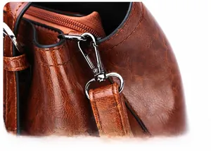 Detail of silver detachable metal hook and stitching on brown patent leather handbag