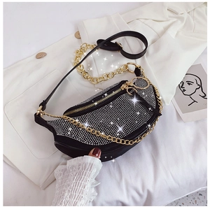 Detail of black rhinestone crescent crossbody bag with gold chain on white blazer background