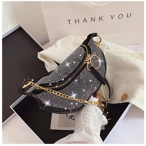 Close-up of sparkling silver rhinestones on a black saddle bag with gold chain strap