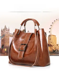 Detail of dark brown faux leather tote bag with metallic buckle and twin handles