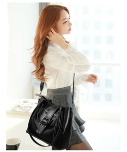 Detail of black faux leather handbag with silver buckle decoration and white stitching