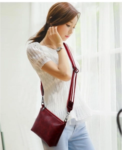 Close-up of burgundy crossbody bag with modern striped wide fabric shoulder strap
