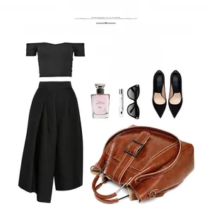 Flat lay of brown vintage leather tote bag with metal buckle and black pleated outfit set