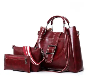 Close-up of three-piece burgundy faux leather handbags set with decorative metal buckles