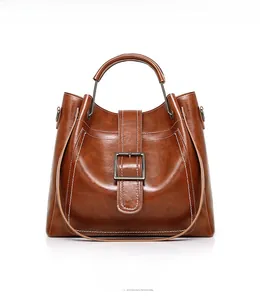 Detail of a brown oil wax leather tote bag featuring square buckle and contrast stitching