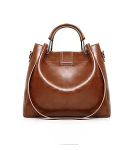 Detail of caramel leather handbag showing white contrast stitching and metallic buckle