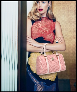 Detailed view of pink Boston bag featuring bone monogram pattern and round metal logo