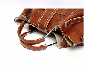 Detail of brown faux leather handbag showing oily wax finish and metal reinforced handle