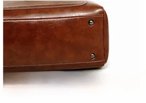 Detailed macro view of brown PU leather bag bottom with protective metal rivets and stitching