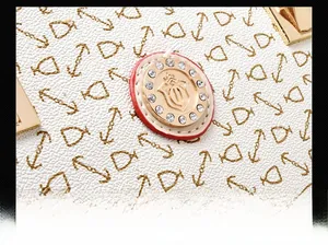 Close-up of golden crown logo with rhinestones on patterned pebble leather handbag