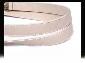 Detail of beige faux leather handle with white stitching and gold metal hardware
