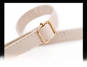 Detail of adjustable golden metal buckle on beige leather shoulder strap with stitching
