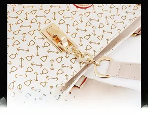 Close-up of light gold hardware chain and bone pattern print on designer handbag