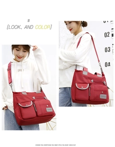 Detail of red waterproof nylon crossbody bag showing multiple zip pockets and adjustable strap