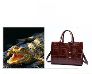 Detail der weinroten Handtasche mit Krokodilprägung und silbernen Metallbeschlägen