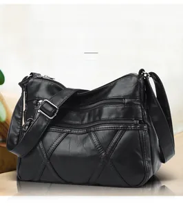 Détail d'un sac bandoulière noir avec multiples zips et coutures décoratives en X