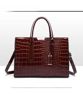 Detail der dunkelbraunen Handtasche mit Krokodilprägung, Metallschnalle und Schultergurt