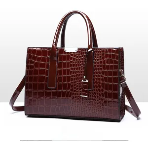 Detail einer eleganten dunkelbraunen Kroko-Handtasche mit Glanzfinish und silberner Metallschnalle