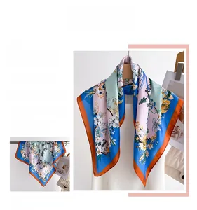 Close-up of floral silk scarf showing digital print details and orange hemmed edges