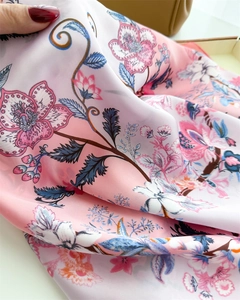 Close-up of silk scarf fabric showing pink floral patterns and smooth satin texture
