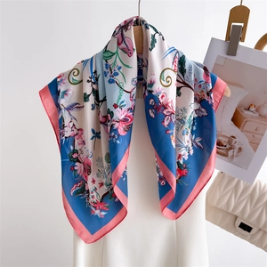 Floral print silk scarf in sky blue and ivory hung elegantly on a wooden hanger