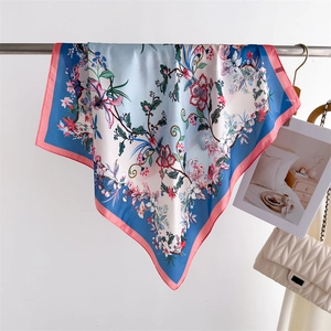 Detailed close-up of floral print silk scarf with pink edges and light blue gradient finish