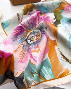 Detailed close-up of high-quality floral print silk scarf with rolled edges and vibrant colors