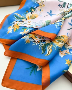 Detailed view of floral silk scarf showing dragonfly print and neat rolled edges