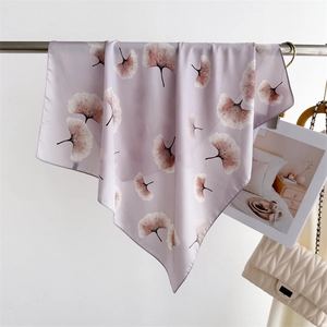 Detail of light purple floral silk scarf with ginkgo leaf pattern hanging on a metal rod