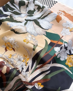 Detail of silk scarf with floral prints and checkered patterns showing smooth glossy texture