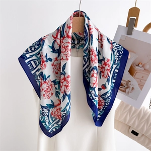 Elegant floral silk scarf with red blossoms and navy border on a white summer dress
