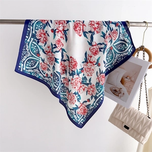 Detail of silk scarf with red floral pattern and navy border hanging on a metal rack