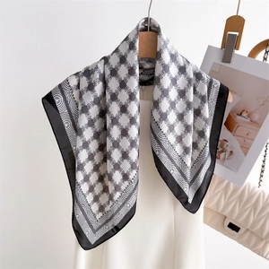 Elegant geometric silk square scarf with H pattern draped on a hanger with a luxury handbag