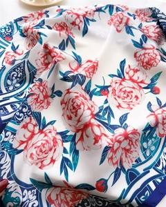 Detailed view of floral silk scarf featuring red peonies and blue vintage tile border