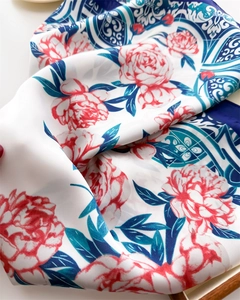 Close-up of silk square scarf featuring vibrant red peony flowers and blue vintage patterns