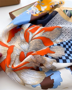 Close-up of silk square scarf featuring artistic floral print and blue checkered pattern